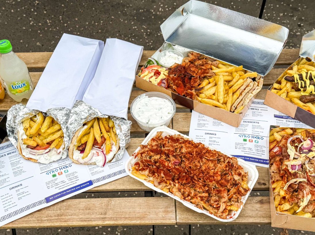  loaded gyros with fries and sauces on a table, ready to eat, from Gyro 
Hero Bearsden 